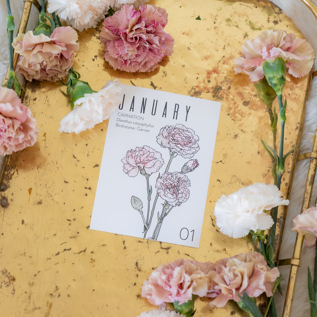 Carnation flowers on a gold tray with a card displaying 'January' and illustrations of carnations.