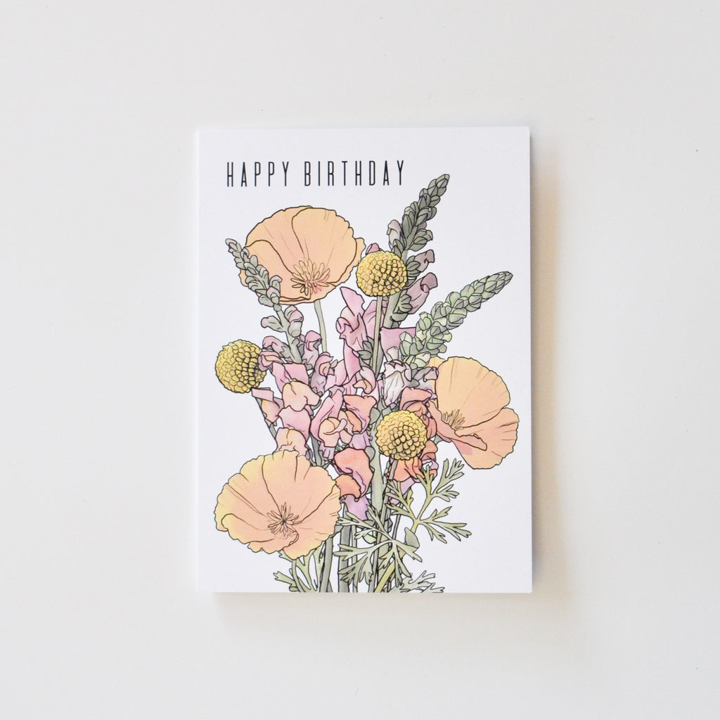 A greeting card that says "happy birthday" and has artwork of california poppies, billy balls, and snapdragon on it.