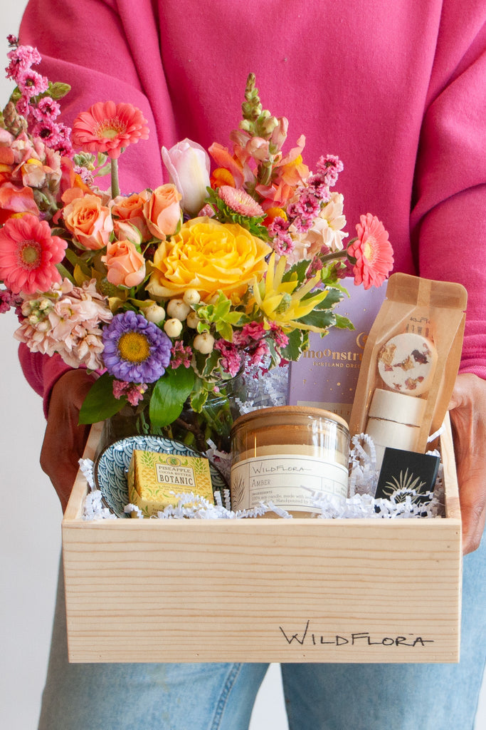 woman holding a wildflora classic gift box with candle flowers chocolate soap dish shower steamers and matches