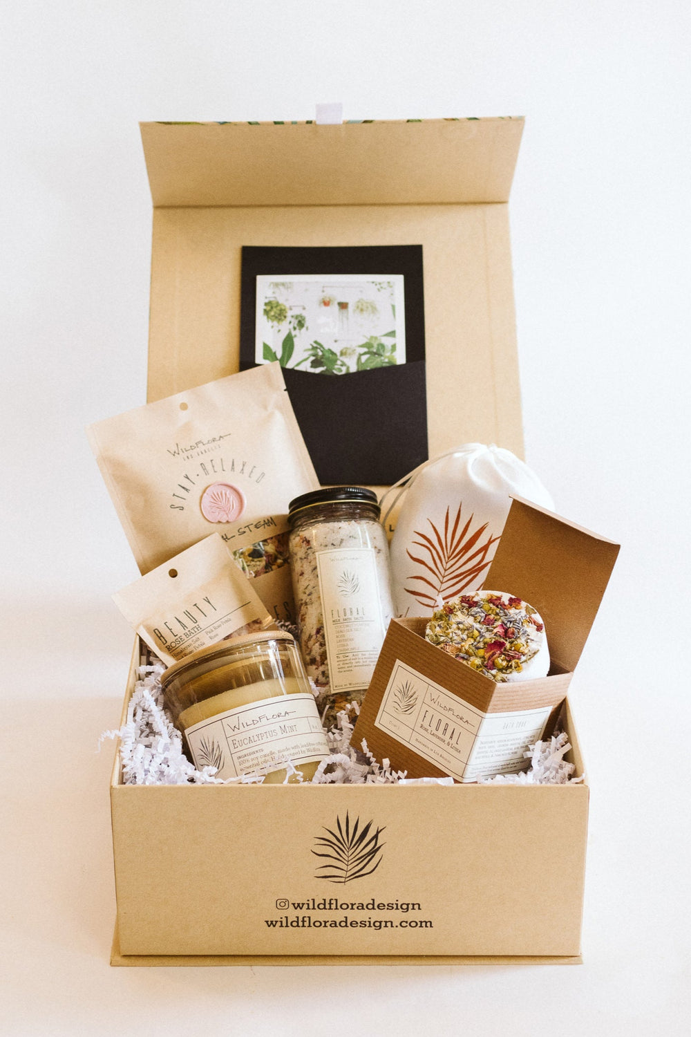 Gift box with candle, bath salts, facial steam, bath soak, and lavender sachet on a white background