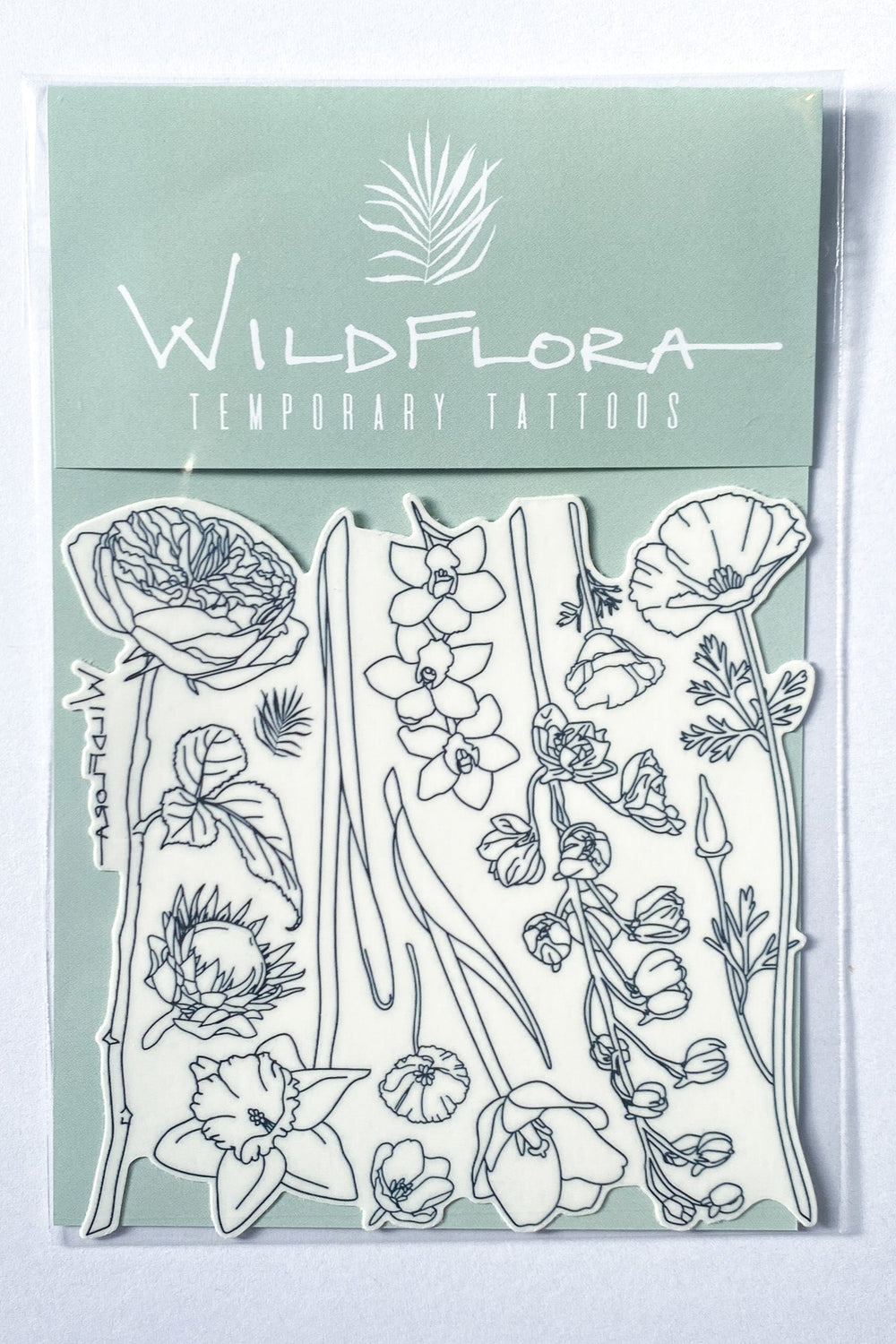 A package of temporary tattoos that are black line drawings of varying flowers, including rose, protea, daffodil, california poppy, tulip, orchid, and delphinium.