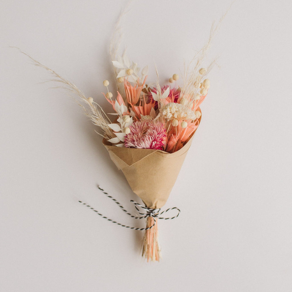 A single mini dried floral bouquet with pink and white flowers, wrapped in brown kraft paper and tied with a black and white string.