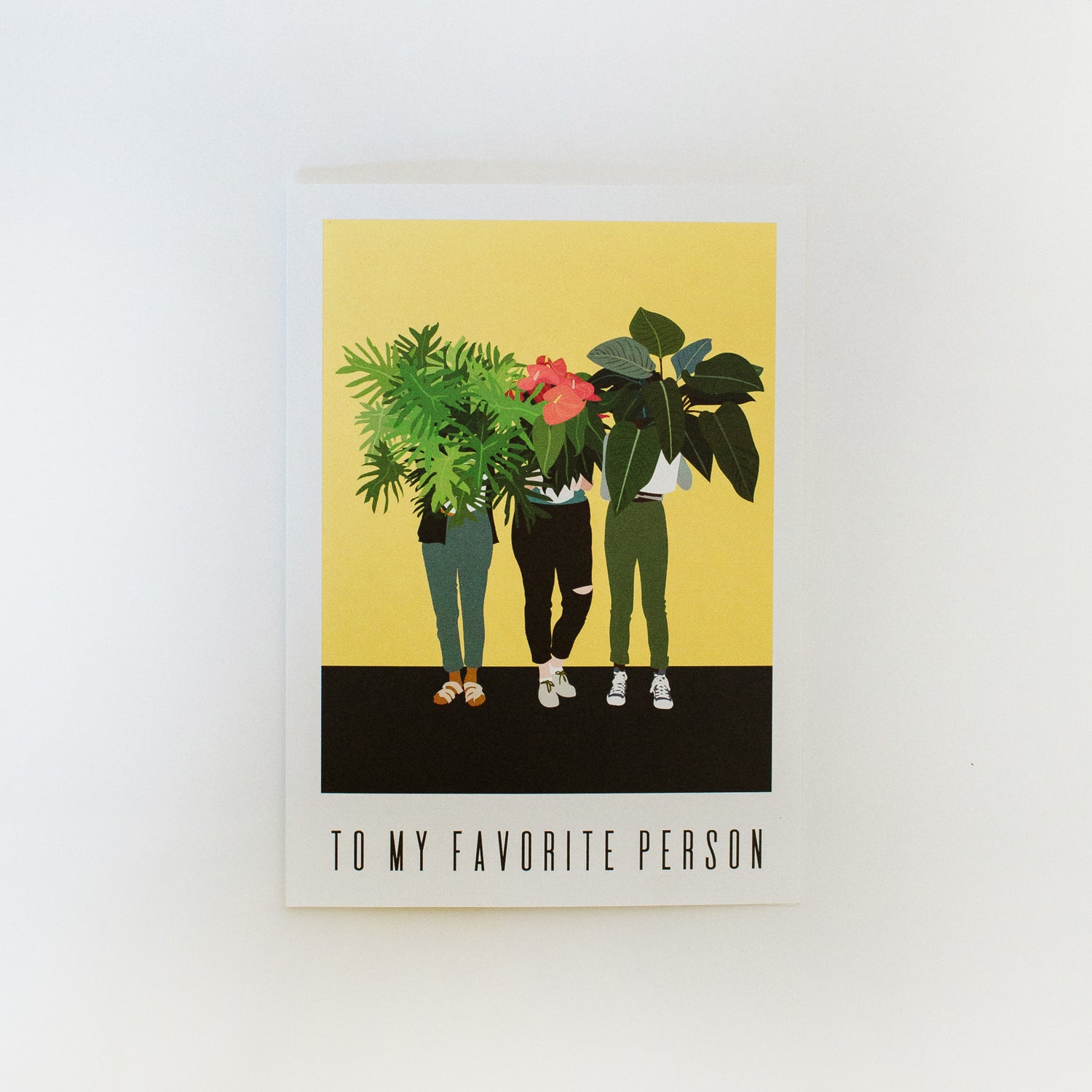 A greeting card that reads "to my favorite person". The artwork on it is of three people holding potted plants in front of their faces.