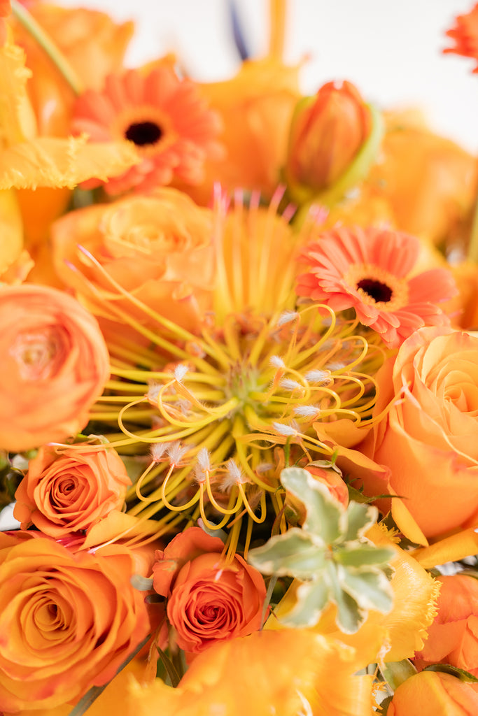 closeup of a pincushion protea in an all orange flower arrangement.