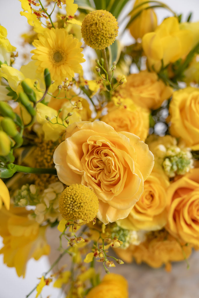 closeup of a rose and billy ball in an all yellow floral arrangement