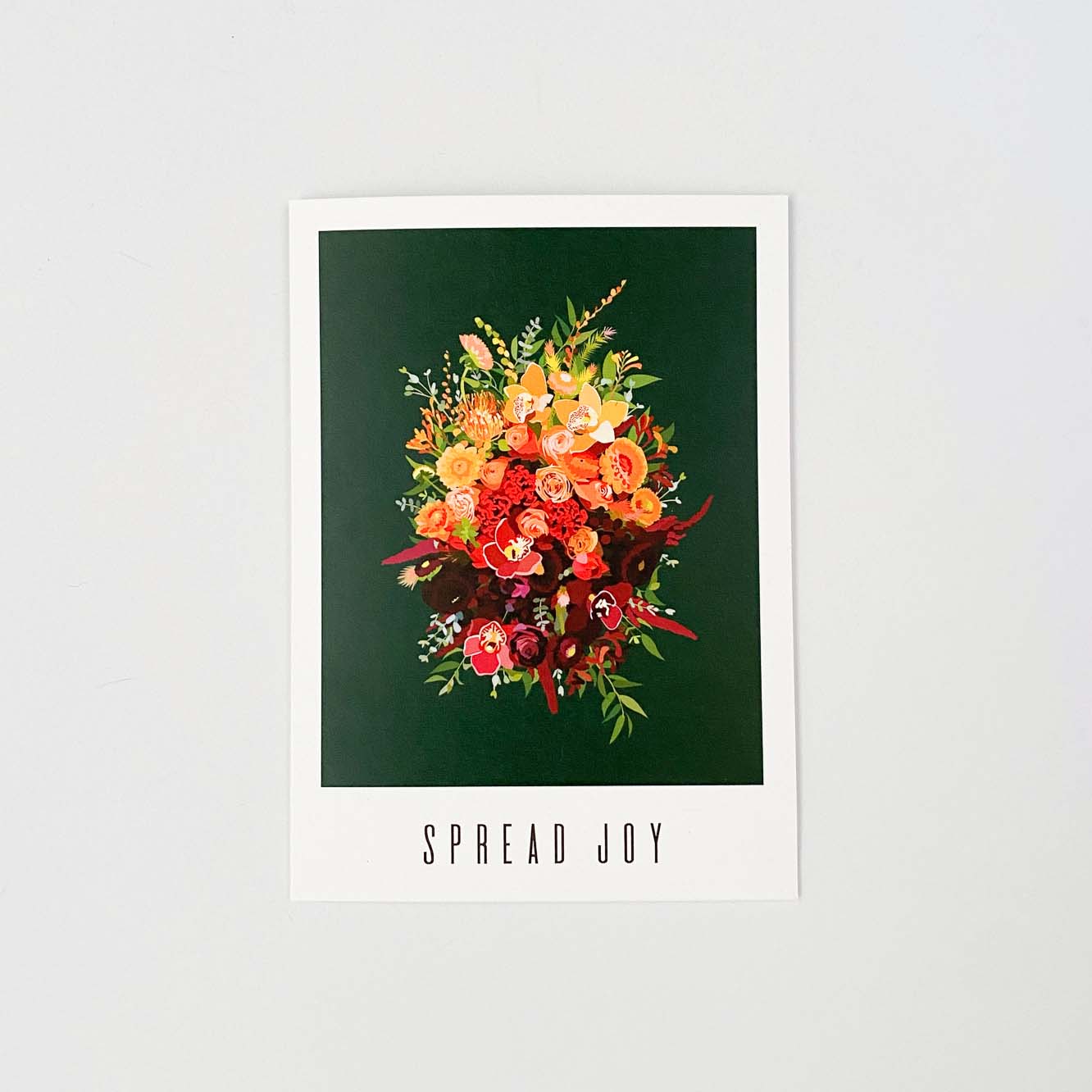 A greeting card that reads "spread joy". The artwork on it is of a gold and red flower bouquet on a dark green background.