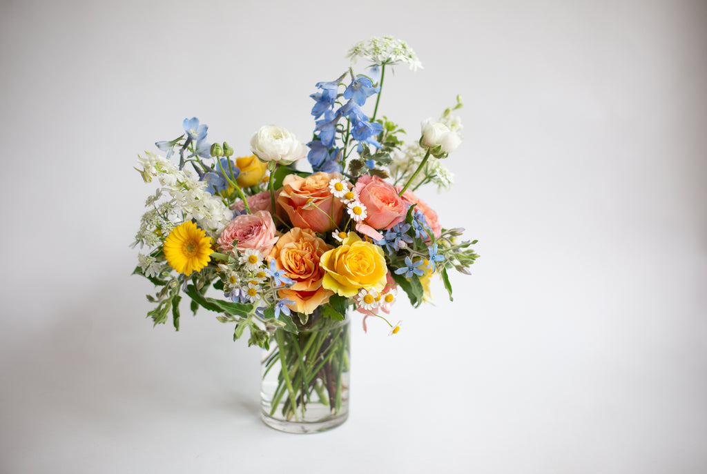 a yellow, tangerine, pink, blue, and white small, hobnail floral arrangement by WildFlora