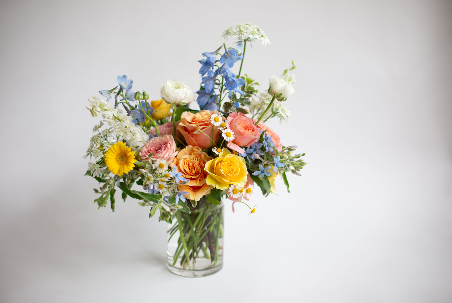 a yellow, tangerine, pink, blue, and white small, hobnail floral arrangement by WildFlora