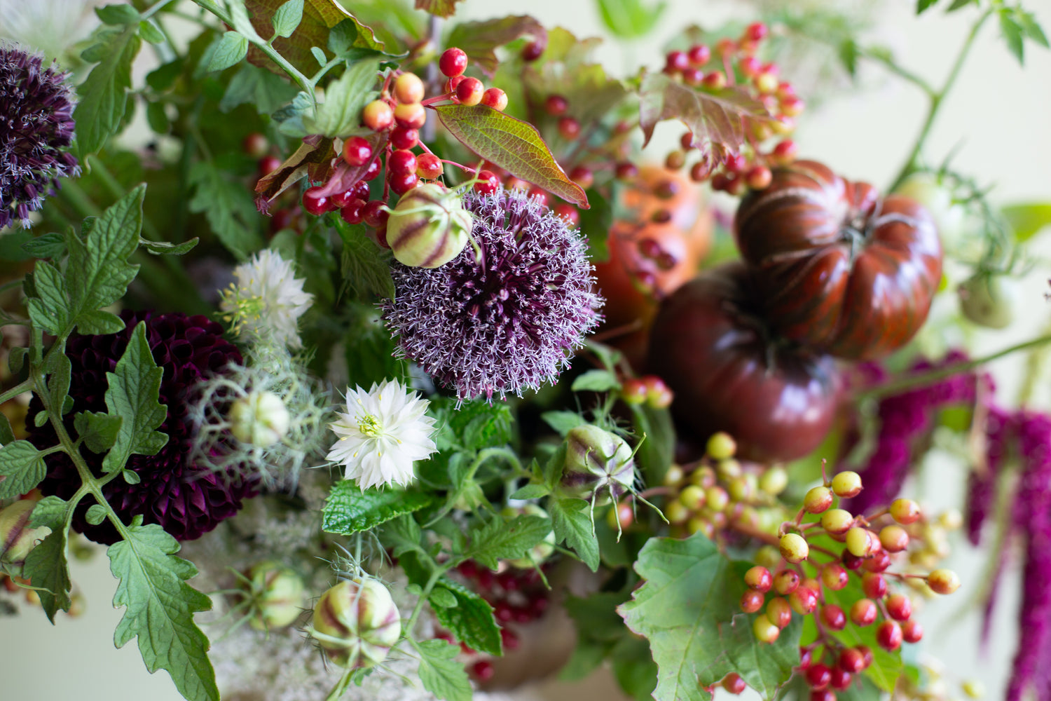 Decorative arrangement of flowers, berries, and small pumpkins with a blurred background