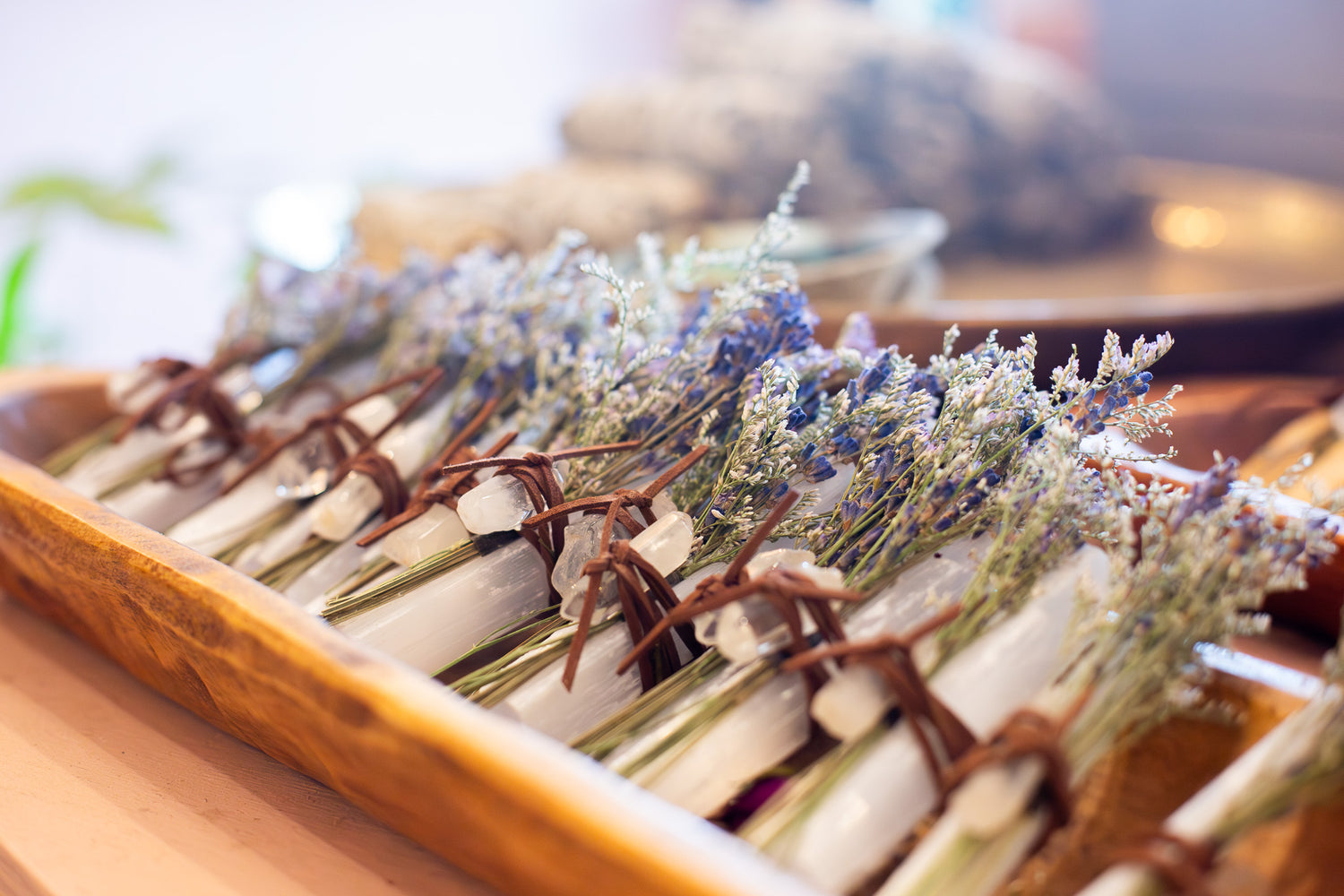 Bouquets of dried flowers tied to selenite crystals in a wooden tray.