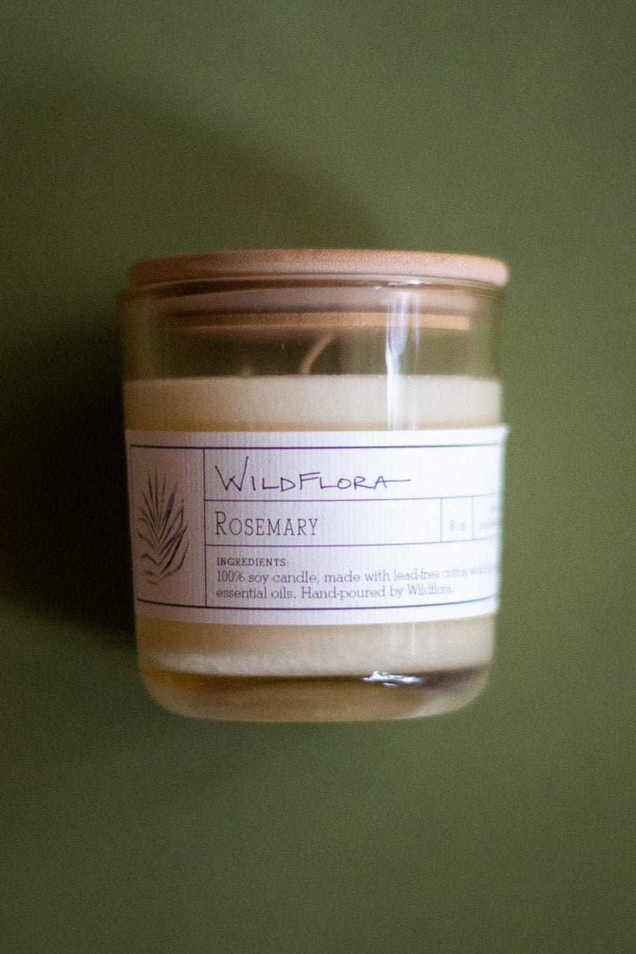 WildFlora Rosemary Candle jar with a label on a green background