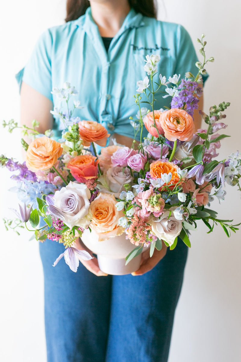 Person holding a colorful bouquet of flowers against a plain background
