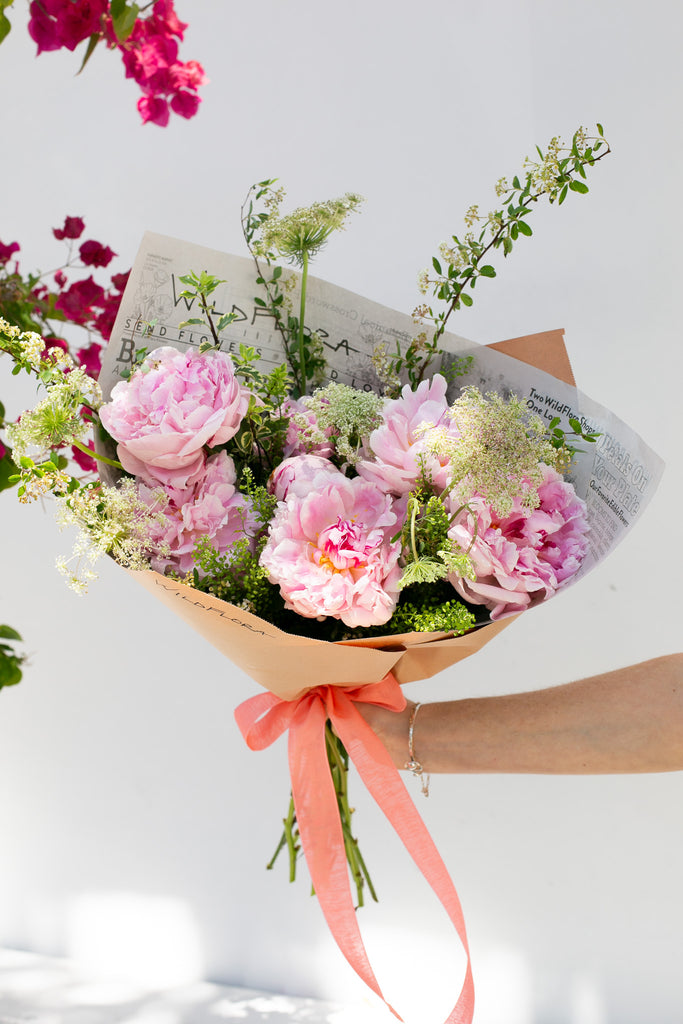 pink peonies and white Queen Ann's Lace wrapped in paper with coral ribbons
