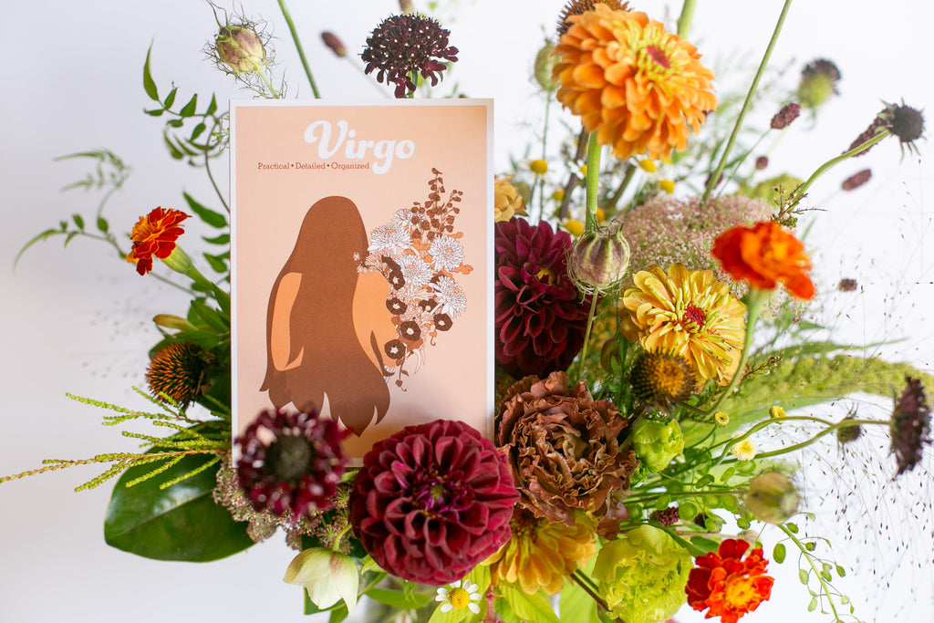 A floral arrangement with a rectangular card featuring the word 'Virgo' and an illustration of a woman's silhouette, set against a white background.