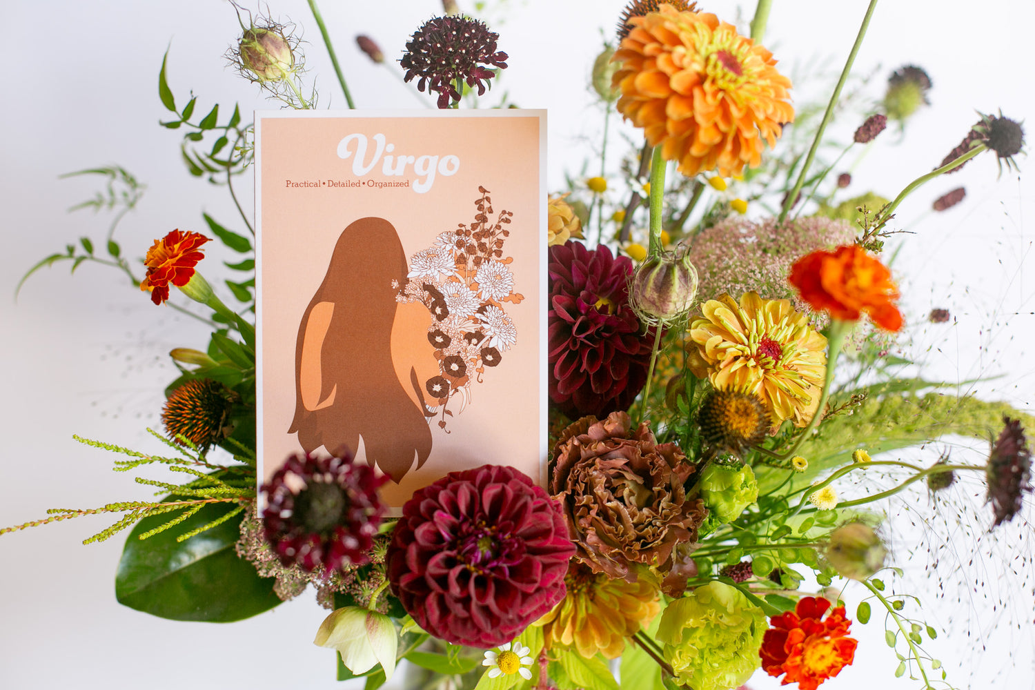 A floral arrangement with a rectangular card featuring the word 'Virgo' and an illustration of a woman's silhouette, set against a white background.