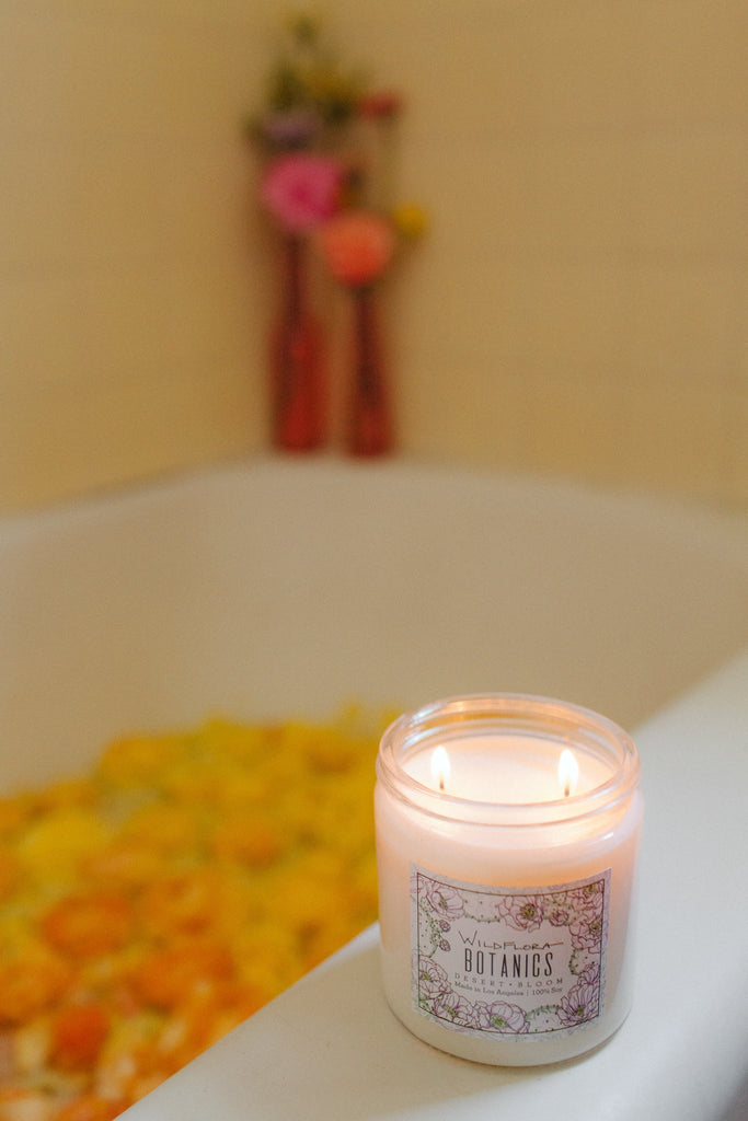 WildFlora double wick Botanics candle on a bathtub filled with water and flowers