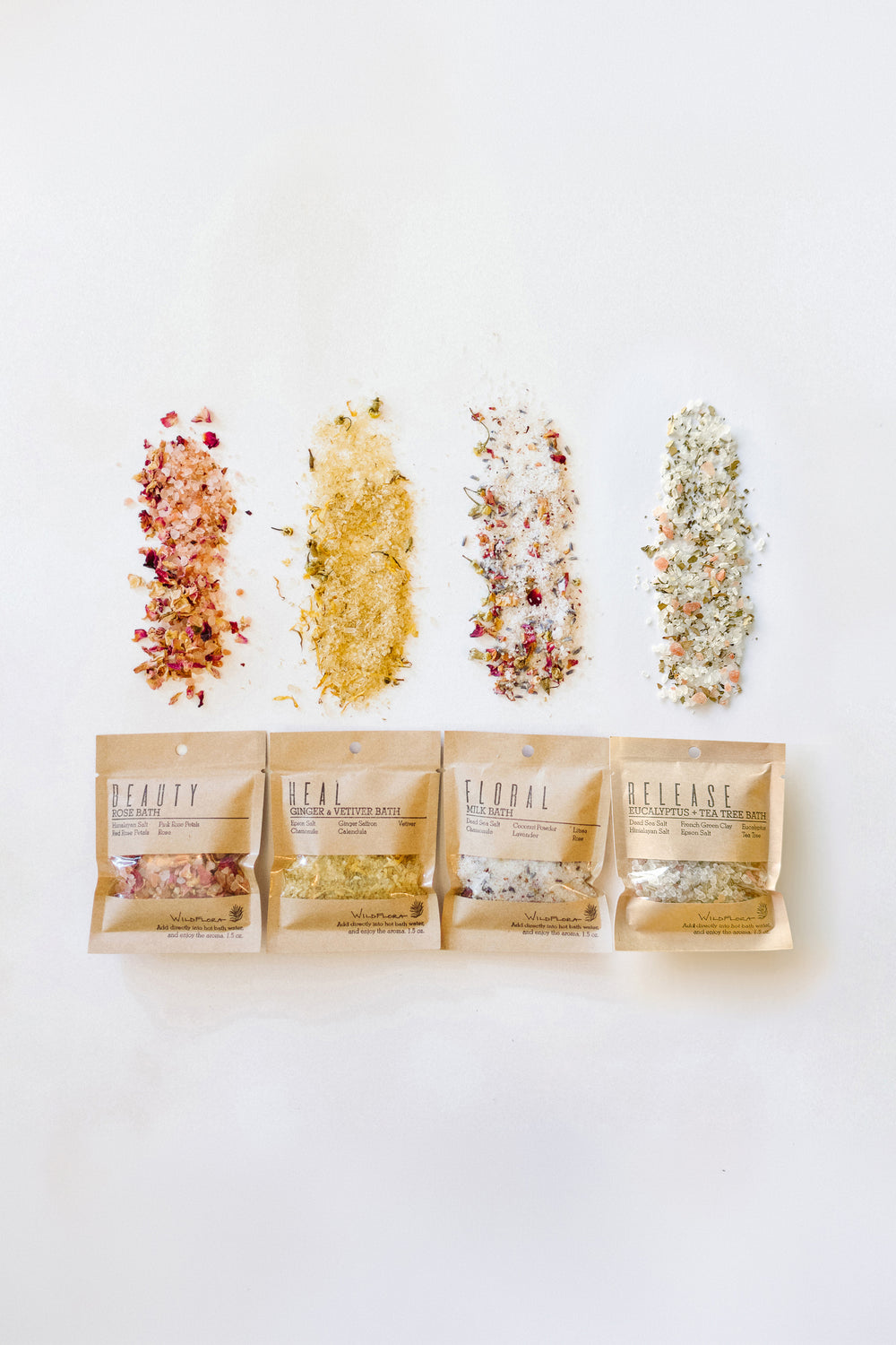 4 packages of WildFlora bath salts, spilled out on a white background