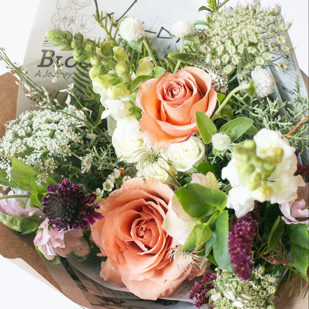 Bouquet of flowers with peach roses and greenery on a white background