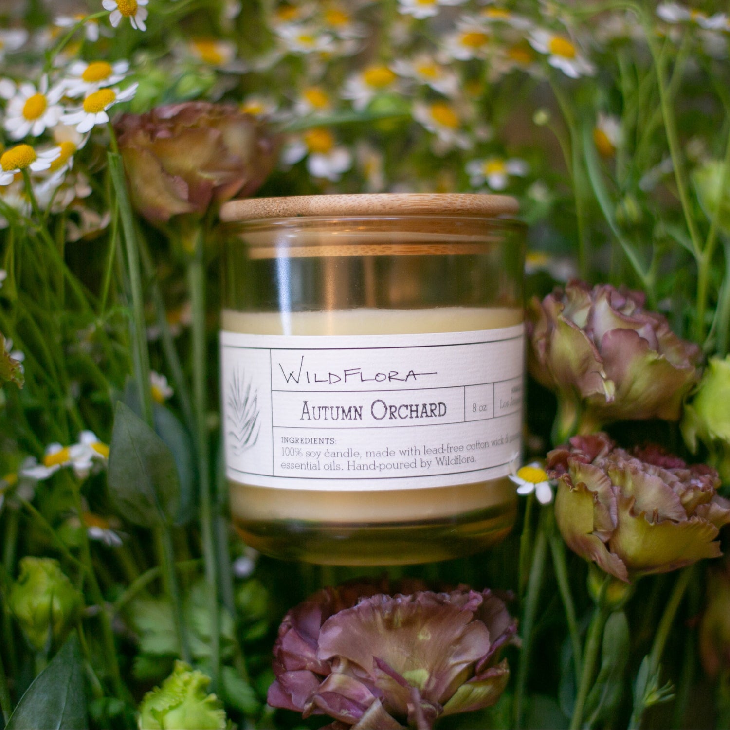 Candle labeled 'Wildflora' surrounded by flowers