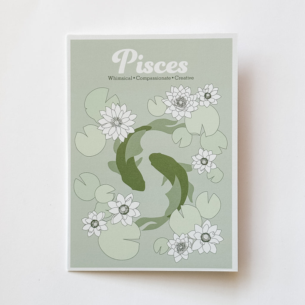 A greeting card featuring a Pisces zodiac design with two koi fish swimming among white lotus flowers and green lily pads on a pale sage background, photographed against a white background.