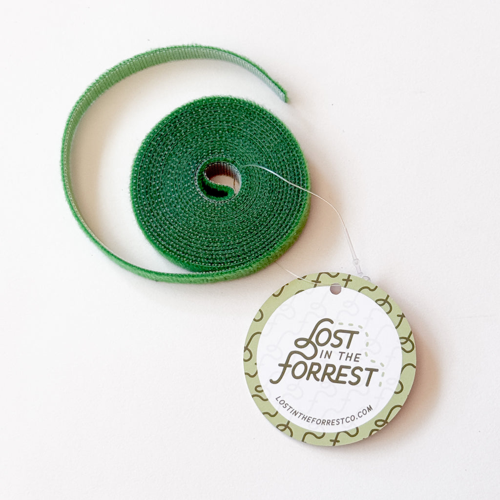 A roll of green velcro on a white background, with a round paper tag attached that reads 'Lost in the Forrest' 