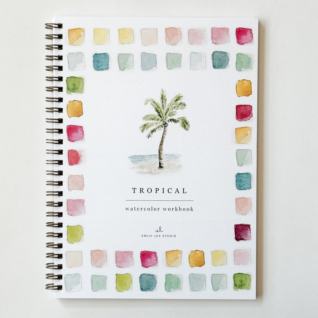 A spiral-bound watercolor workbook titled 'TROPICAL watercolor workbook' with a central palm tree illustration and a border of colorful watercolor swatches, photographed on a light neutral background.