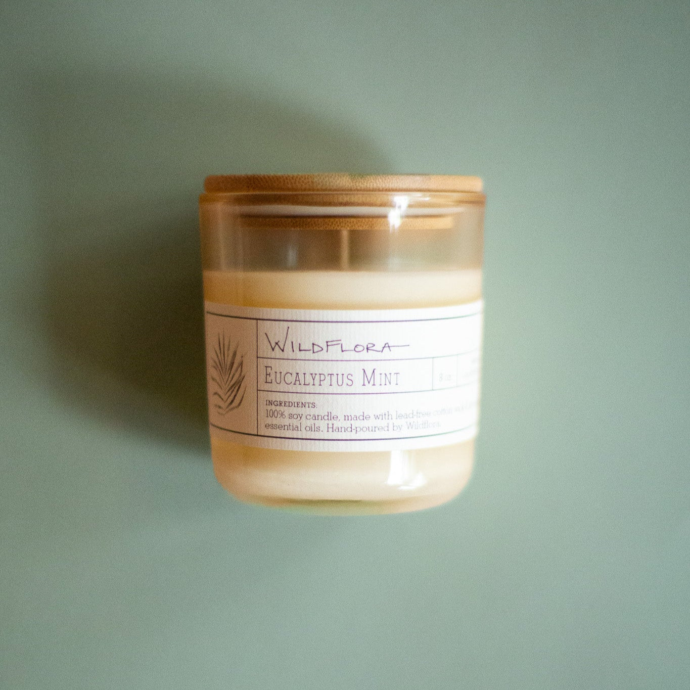 WildFlora Eucalyptus Mint Candle with a wooden lid on a green background