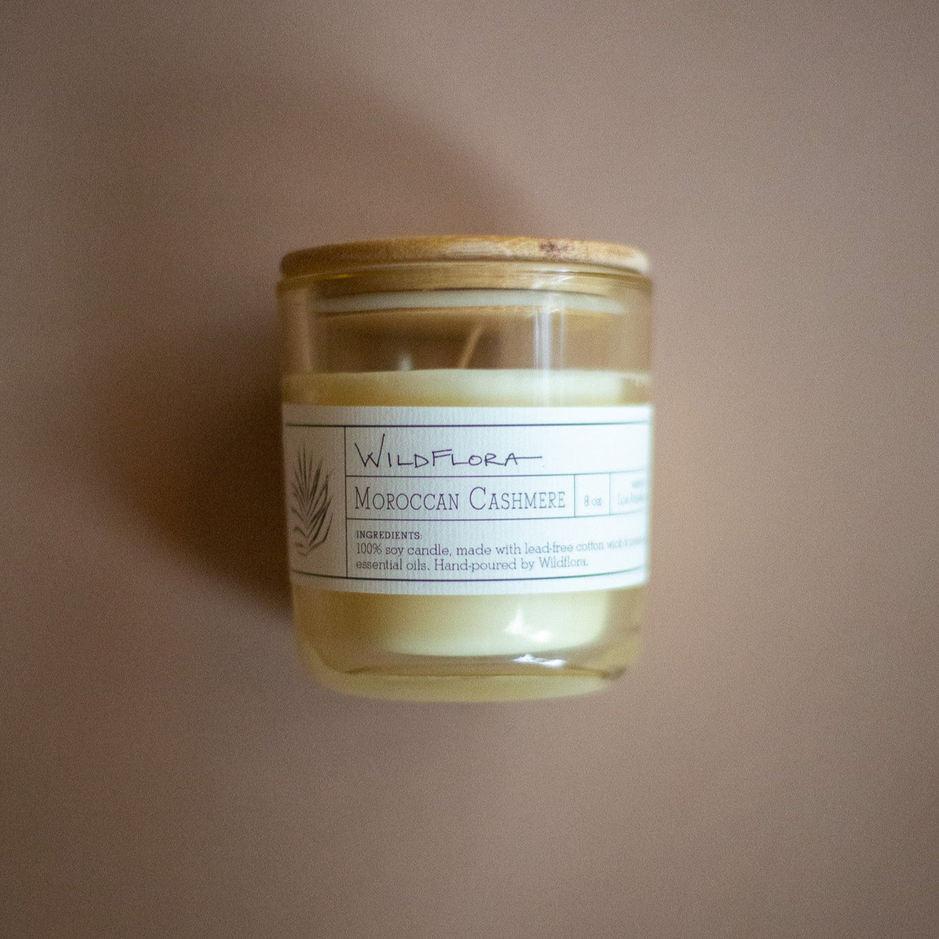 WildFlora Moroccan Cashew candle with a wood lid on a beige background