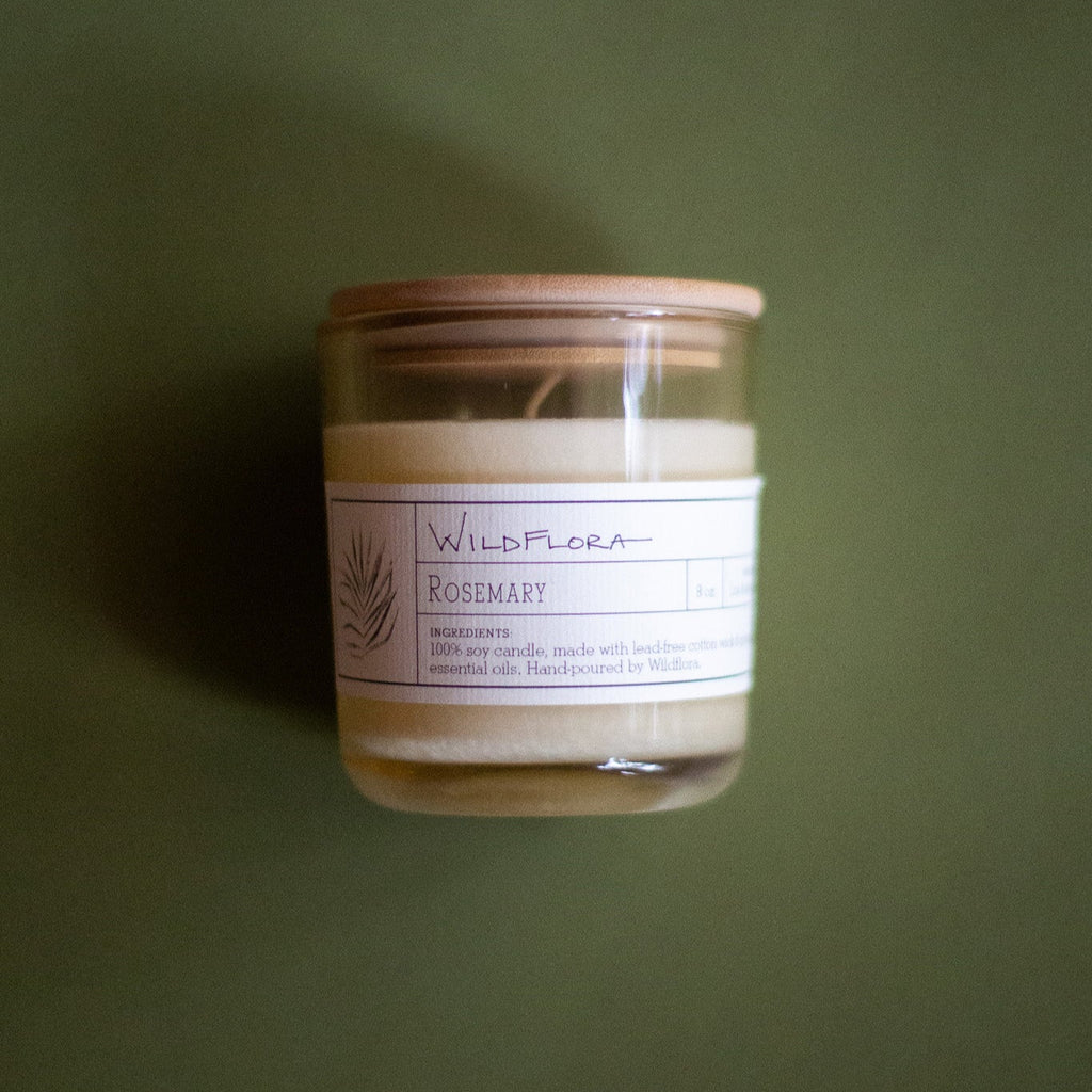 WildFlora Rosemary Candle jar with a label and wood lid on a green background