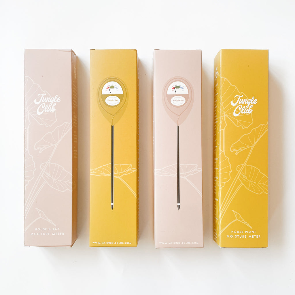 dusty rose and mustard colored plant moisture meters in similar-colored boxes, photographed on a clean white background.